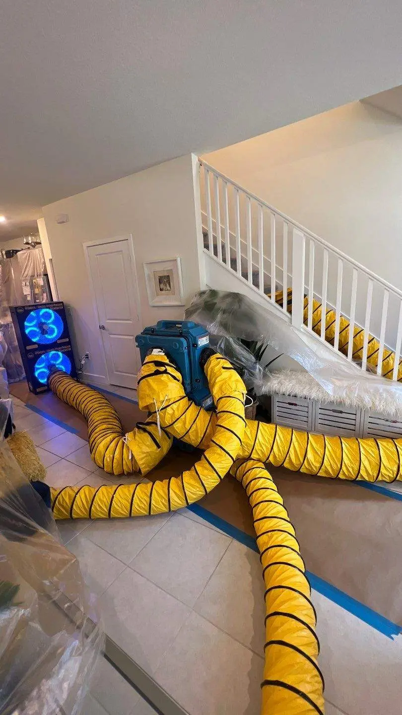 FixMold mold drying setup with yellow ventilation hoses and air movers in a house interior