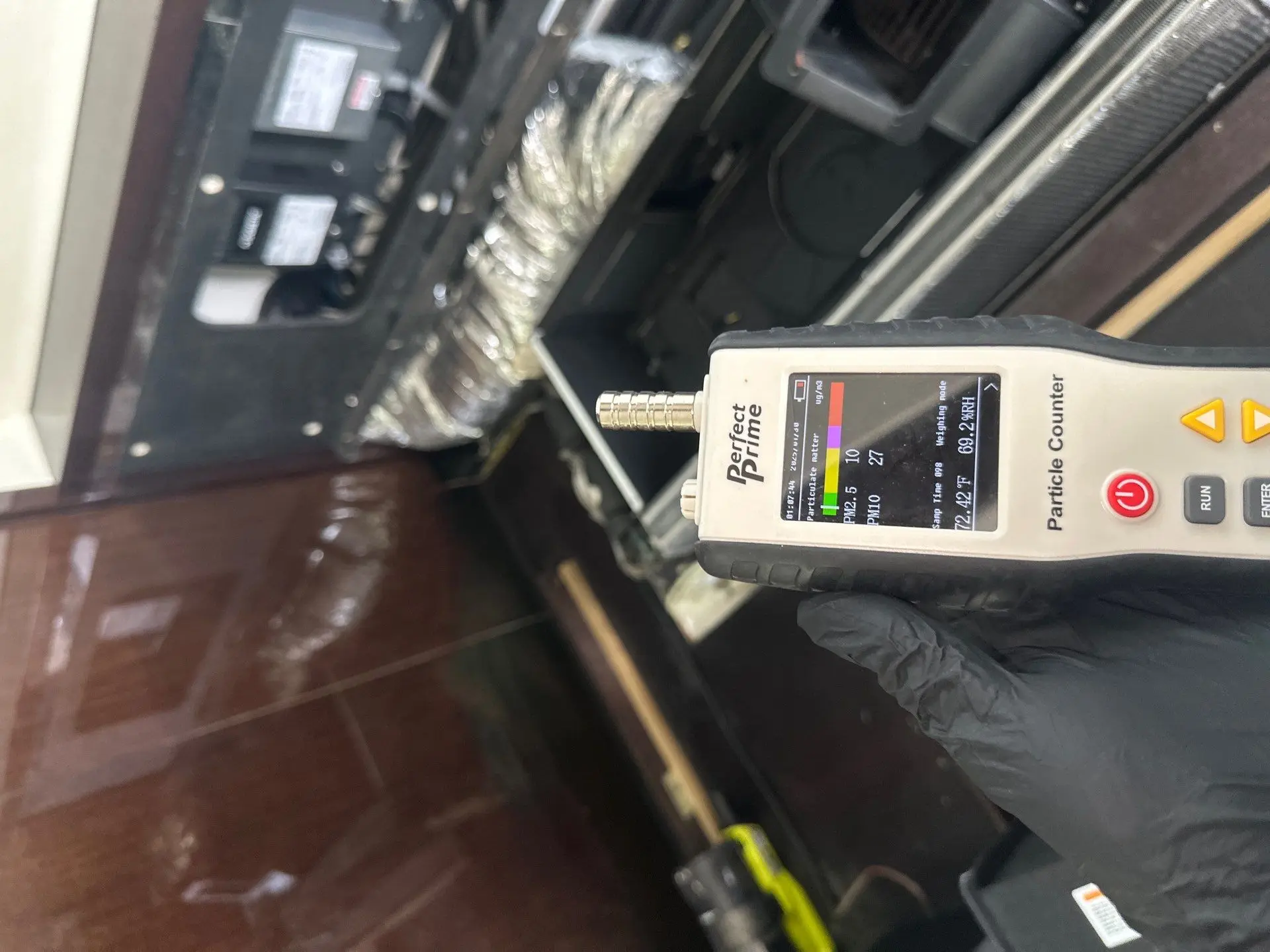 Technician’s gloved hand using mold inspection meter with visible readings in residential living room